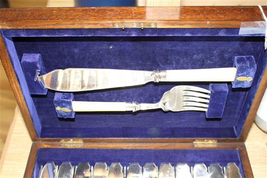 A cased set of twelve pairs of plated fish knives and forks with servers, silver banded ivorine handles